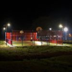 il y a un terrain de sport éclairé avec des lampadaires solaires solamaz avec des enfants qui jouent le soir au football